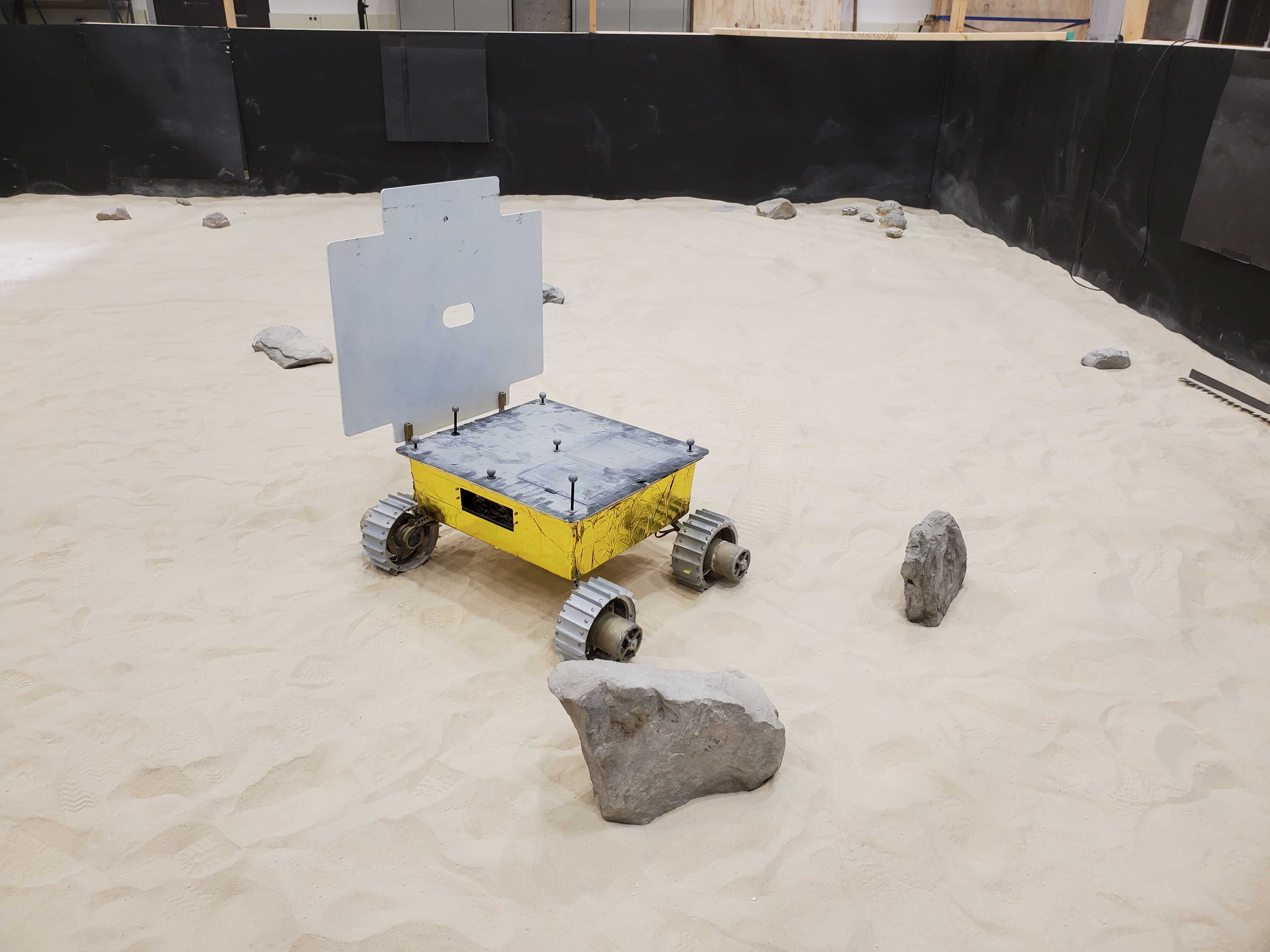 Prototype rover in test bed with rocks.